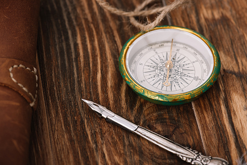 close up view of compass near nib on brown wooden surface