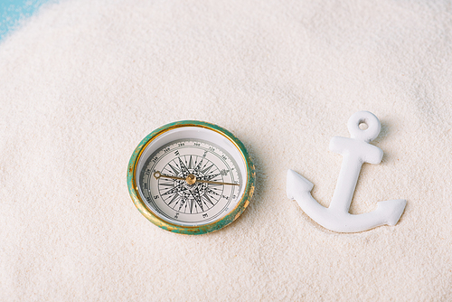 compass and plastic anchor on white sand