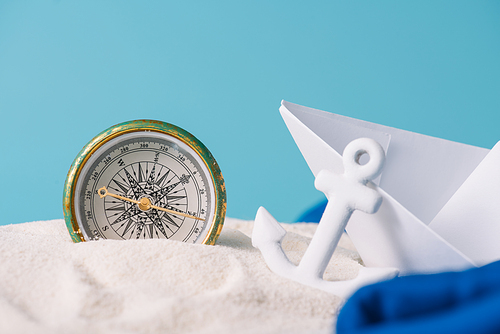 white sand with paper boat, anchor and compass isolated on blue