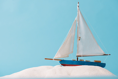decorative ship in white sand isolated on blue