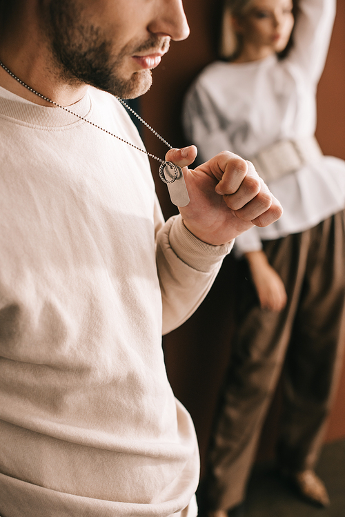 cropped view of young man touching pendants and blonde girl on brown