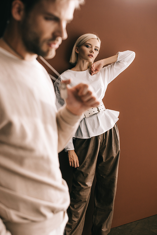 selective focus of young man and blonde girl in white blouse on brown