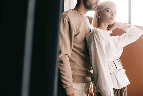 cropped view of stylish couple standing near curtain