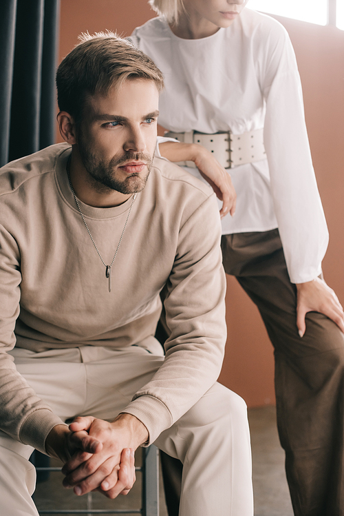 cropped view of stylish couple near curtain on brown