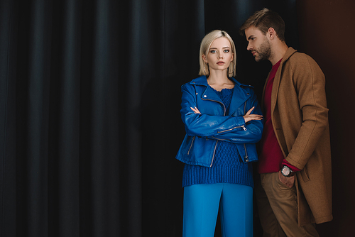 stylish couple in autumn outfits standing near curtain