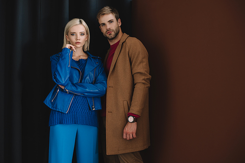 stylish couple in autumn outfits standing near curtain