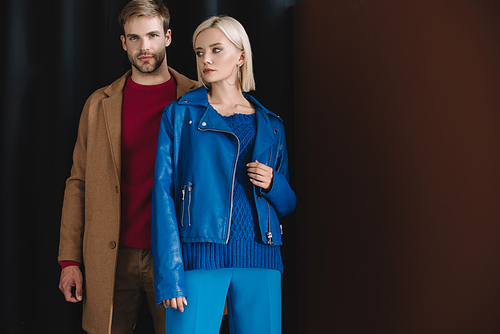 stylish couple in autumn outfits standing near curtain