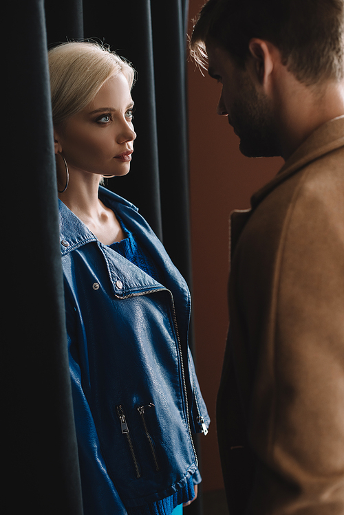 stylish young woman and man in autumn outfits looking at each other