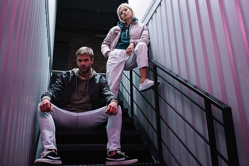 stylish young man and woman in casual autumn outfits on stairs