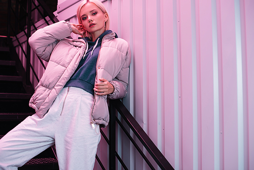 blonde young woman in down jacket  on stairs