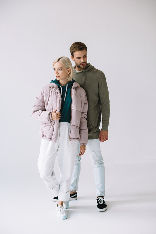 full length view of stylish blonde girl and bearded man on grey