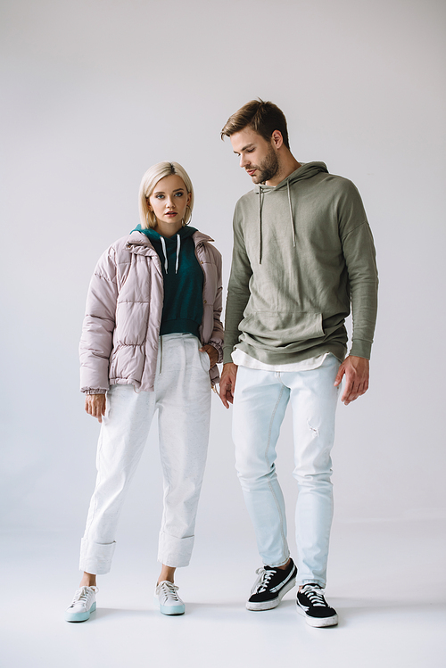 full length view of stylish blonde girl and bearded man on grey