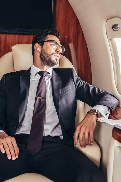 handsome businessman in suit listening music in private plane