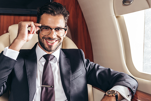 handsome businessman in glasses smiling and  in private plane