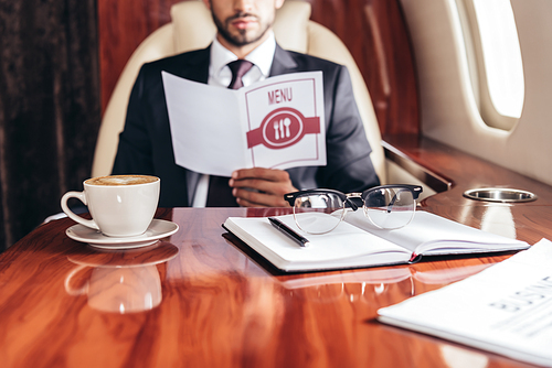 selective focus of cup of coffee, notebook and glasses in private plane