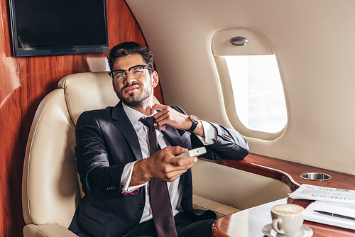 handsome businessman in suit holding remote controller in private plane