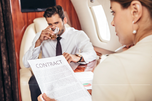 selective focus of businesswoman holding contract in private plane