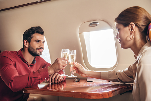 boyfriend and girlfriend clinking with champagne glasses in private plane