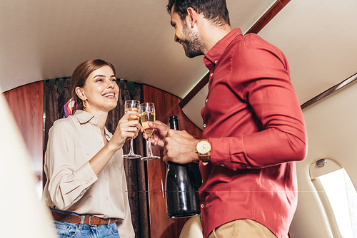 boyfriend and girlfriend clinking with champagne glasses in private plane