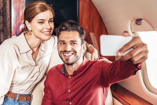 selective focus of boyfriend and girlfriend talking selfie in private plane