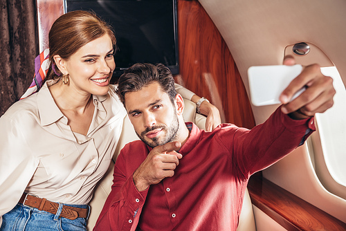 selective focus of boyfriend and girlfriend talking selfie in private plane