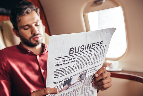 handsome man in shirt reading business newspaper in private plane