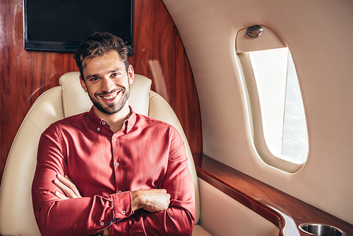 handsome and smiling man in shirt with crossed arms in private plane