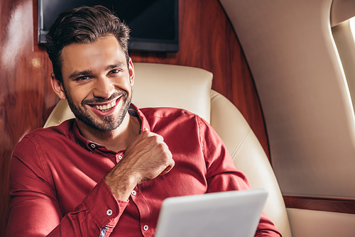 smiling man in shirt holding digital tablet in private plane