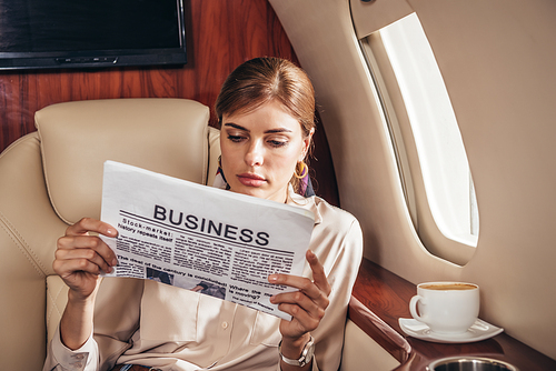 attractive woman in shirt reading newspaper business in private plane