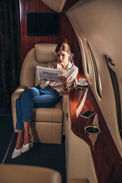 attractive woman in shirt reading newspaper business in private plane