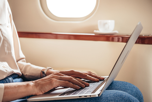 cropped view of woman using laptop in private plane