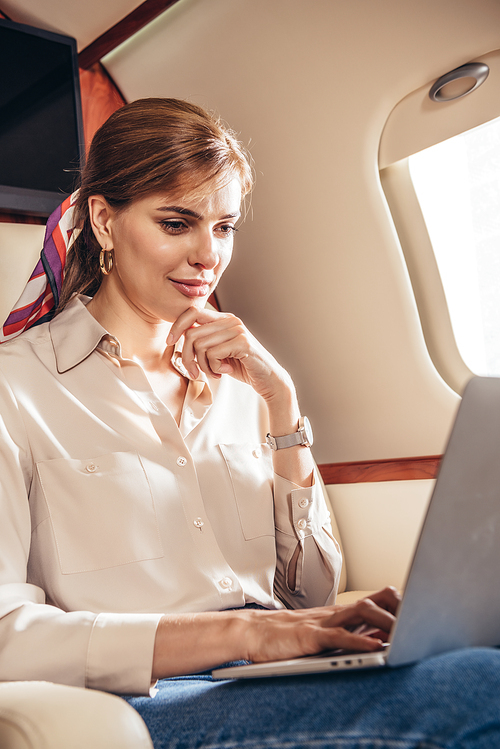 attractive woman in shirt using laptop in private plane