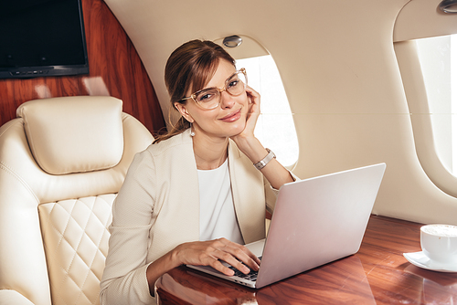 attractive businesswoman in suit with laptop  in private plane