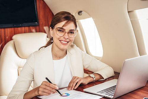 smiling businesswoman in suit doing paperwork in private plane