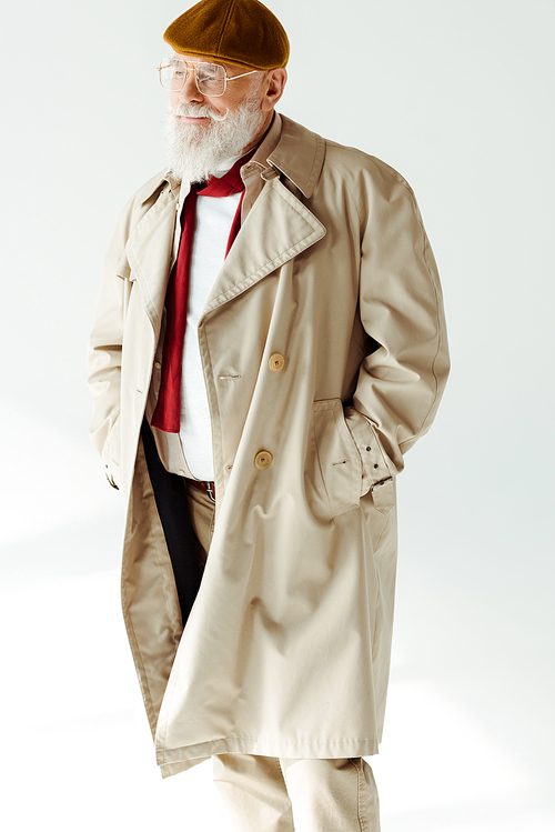 Handsome elderly man in coat and beret looking away on white background