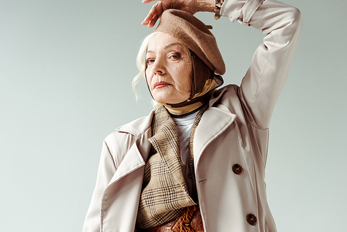 Fashionable elderly woman in trench coat  while posing isolated on grey