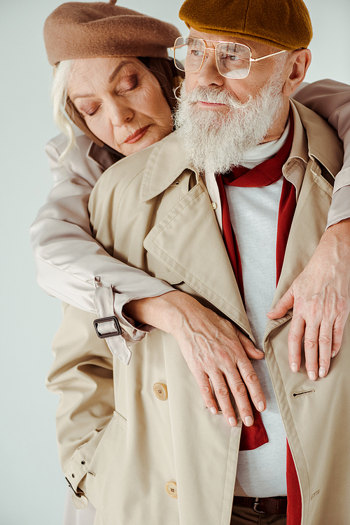 Stylish senior woman embracing handsome man isolated on grey