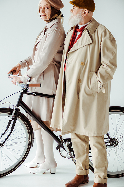 Elegant senior woman with bicycle  near handsome man on white background
