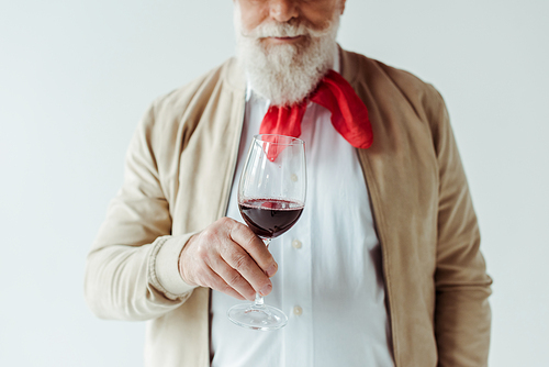 Cropped view of elegant senior man holding glass of red wine isolated on white
