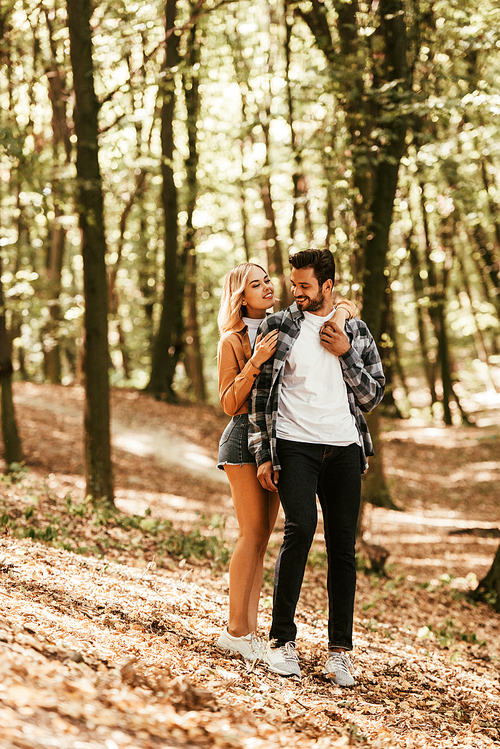 happy girl embracing handsome boyfriend while walking in park