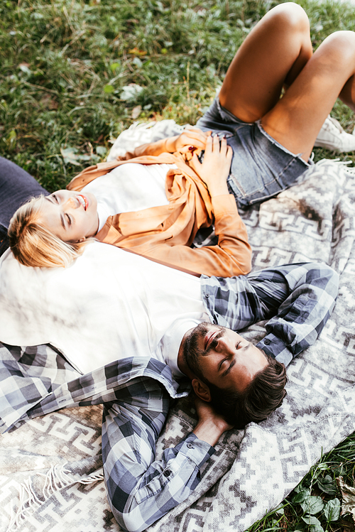 overhead view of happy young couple lying on blanket in park