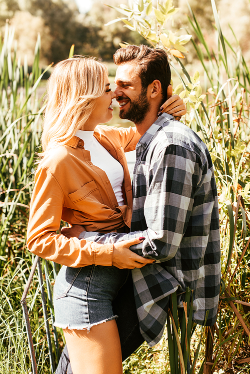 happy young couple hugging in thicket of sedge