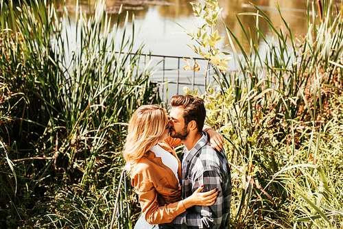 happy young couple embracing and hugging in thicket of sedge near lake