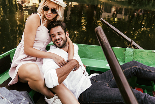 attractive young woman hugging happy boyfriend while sitting in boat