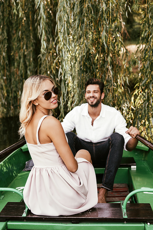 attractive young woman  while sitting in boat near happy boyfriend