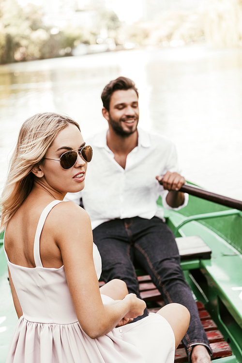 attractive girl in sunglasses  while sitting in boat with boyfriend