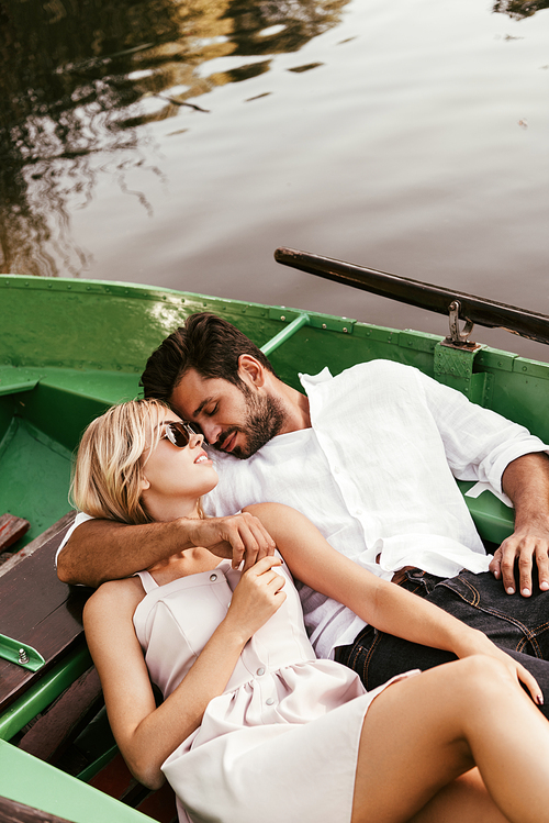 happy young couple embracing while relaxing in boat on lake