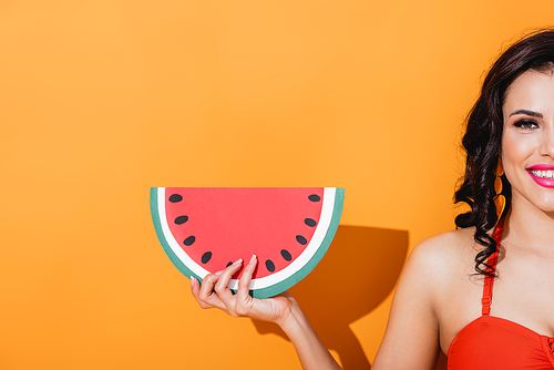 cropped view of cheerful woman holding paper cut watermelon on orange
