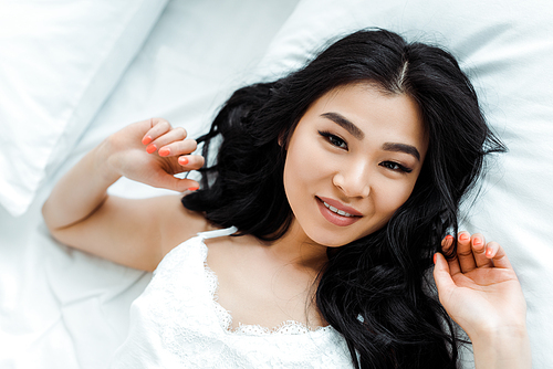 overhead view of happy asian girl lying on bed at home