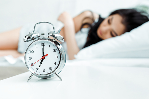 selective focus of retro alarm clock near sleeping girl